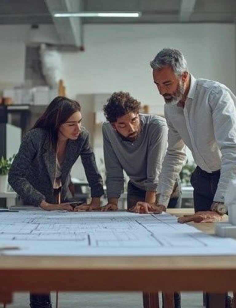 Tre arkitekter gennemgår bygningstegninger ved et arbejdsbord