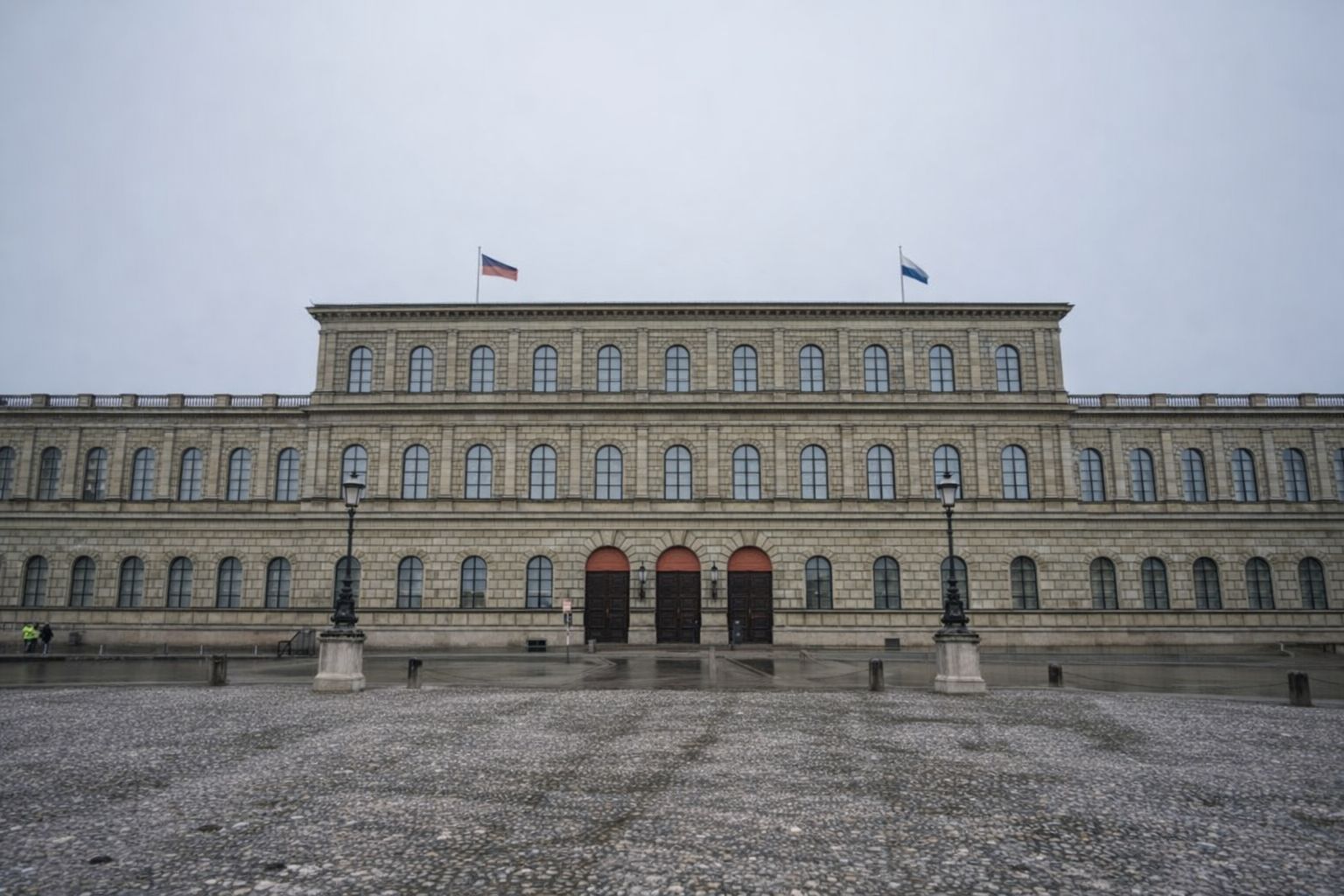 Stor klassisk stenbygning med symmetriske buede døre og vinduer.